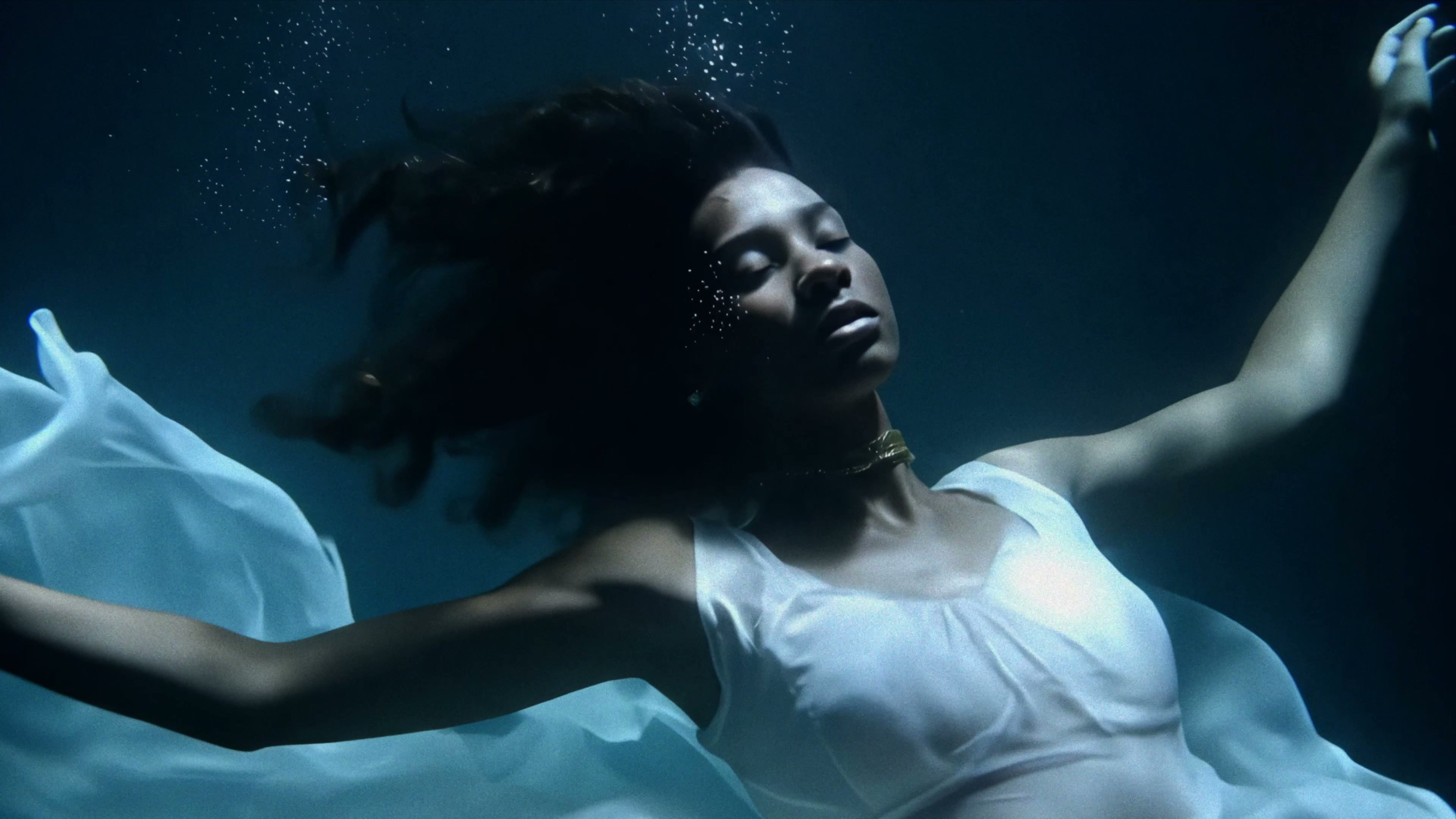 Alexandra Oz. in «Echoes» — submerged in a white dress, drifting beneath the surface.