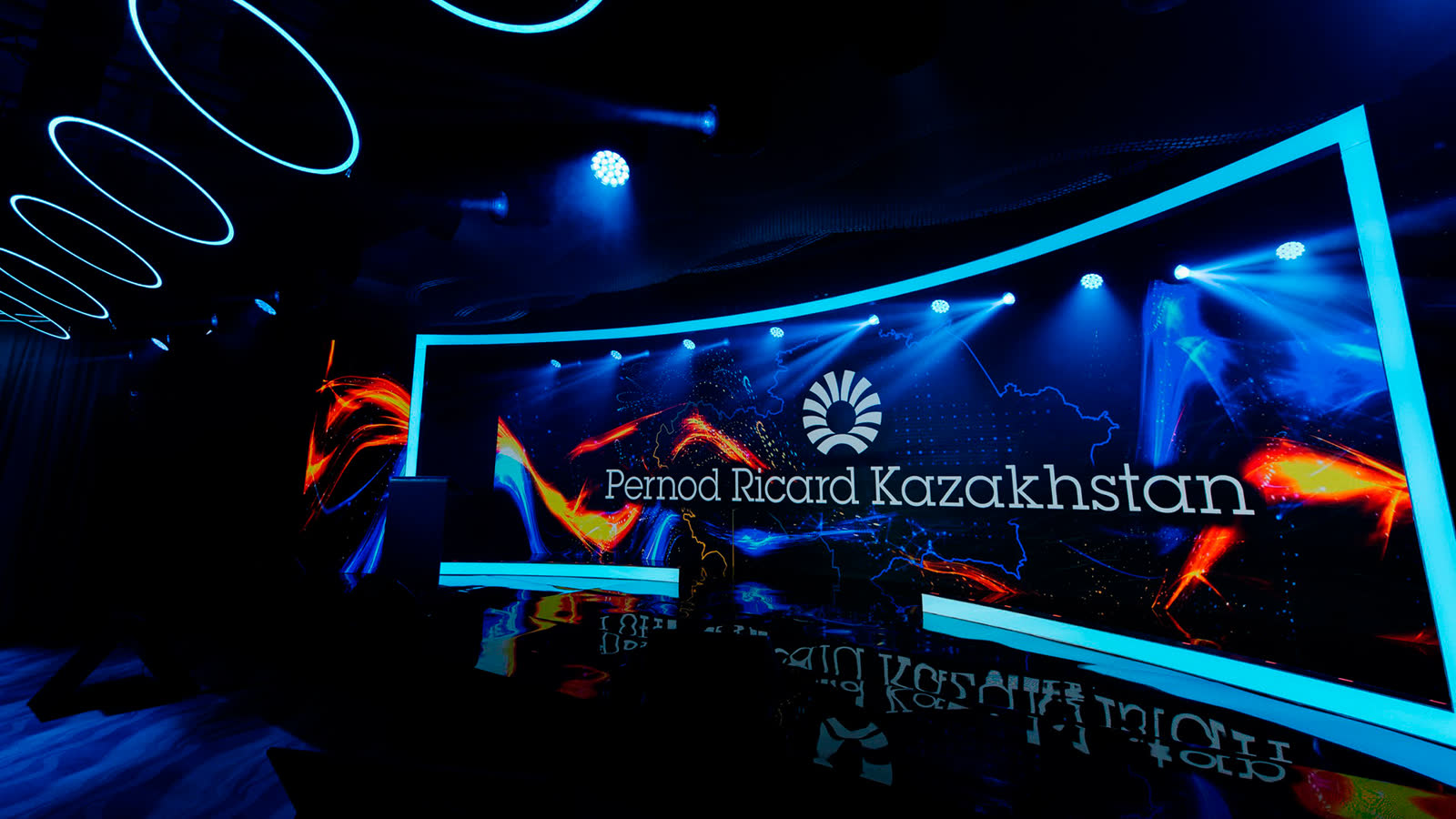 The congress stage under a ceiling grid of lit rings, the brand mark drawn in light.