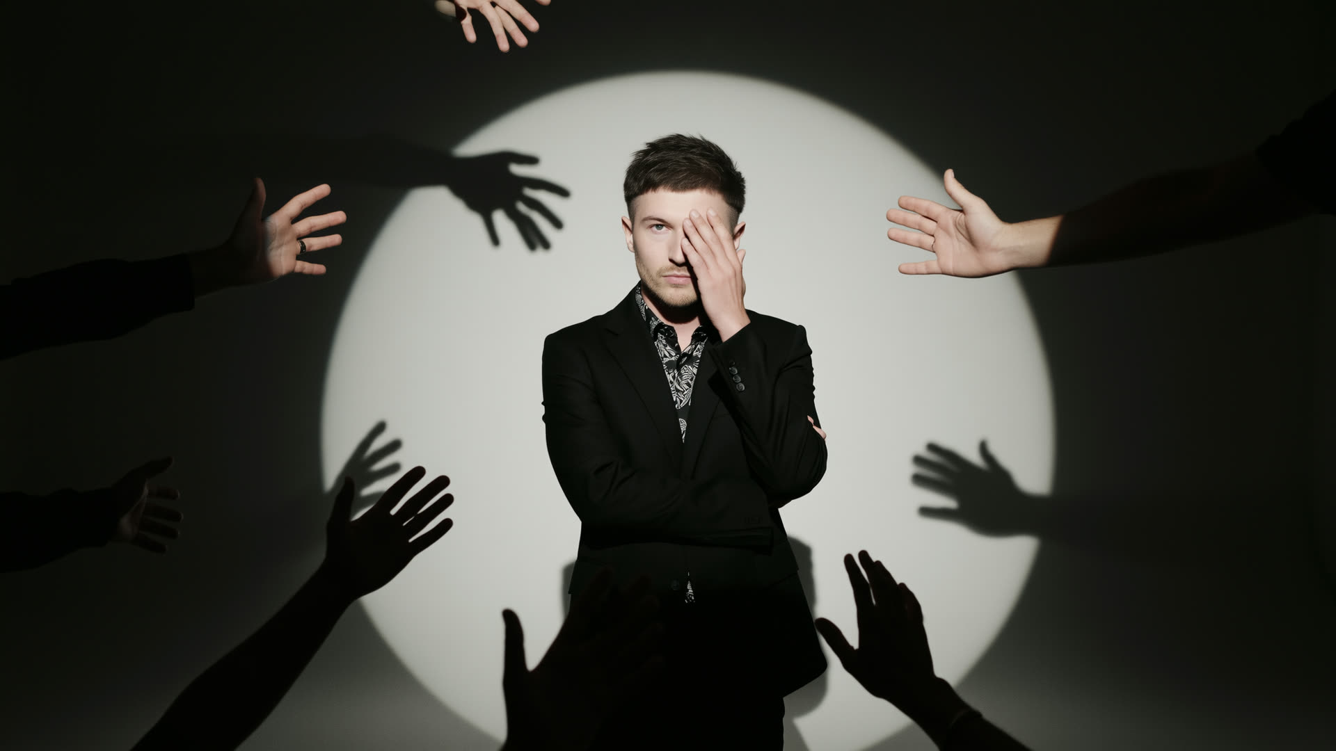 The spotlight and the hands — grief reaching in from the dark